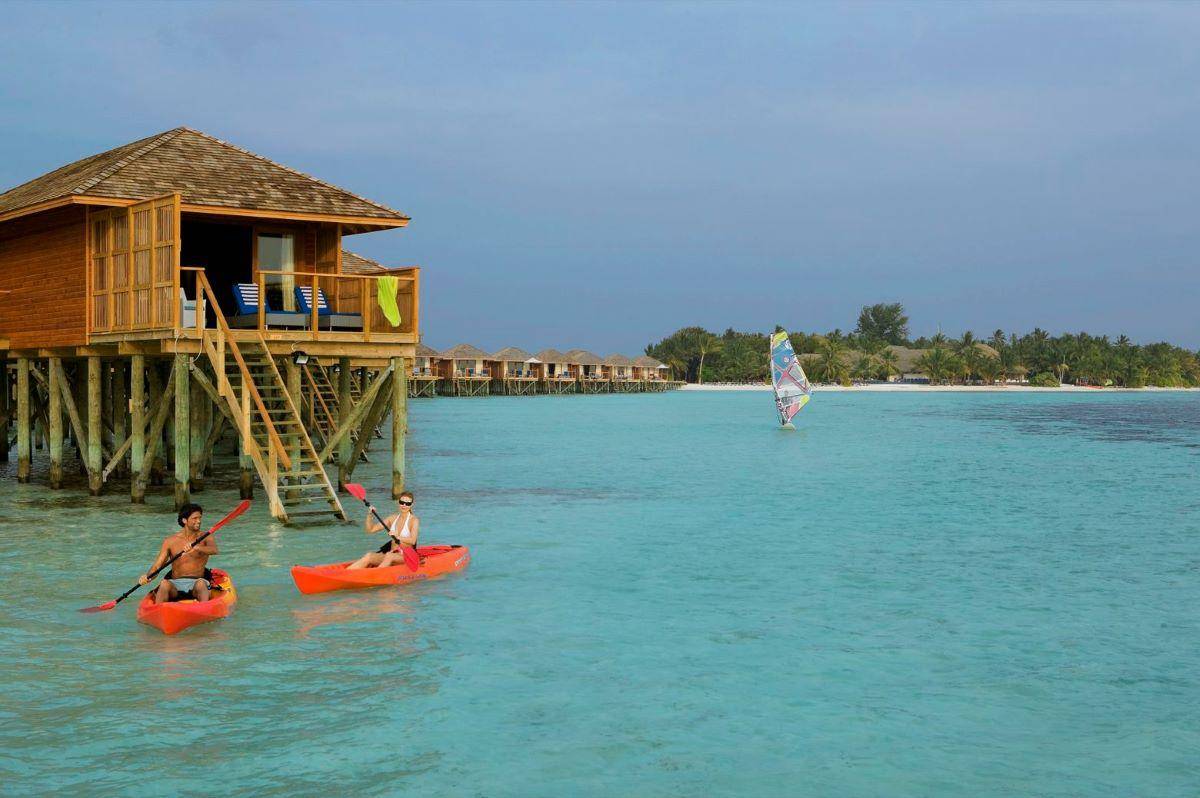 Vilamendhoo Island Resort, Malediven, Jacuzzi Water Villa, Außenansicht Wasservilla mit Paar im Kajak